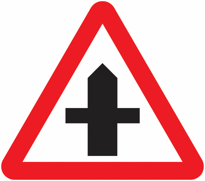 UK triangular warning sign with a red border showing a black crossroad symbol ahead.