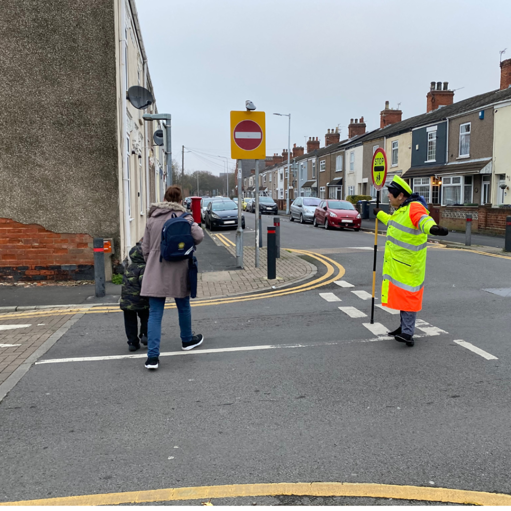 School crossing patrol (lollipop lady) holding a STOP - Children sign in the road